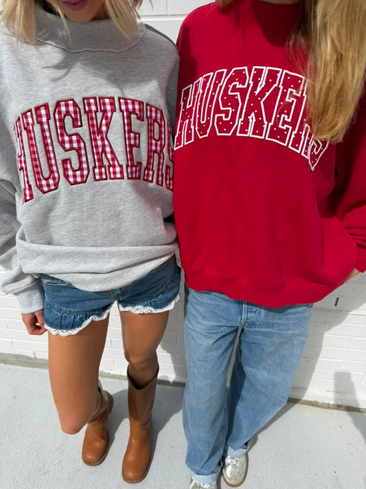 Two models wearing gray and red Nebraska Huskers mockneck sweatshirts