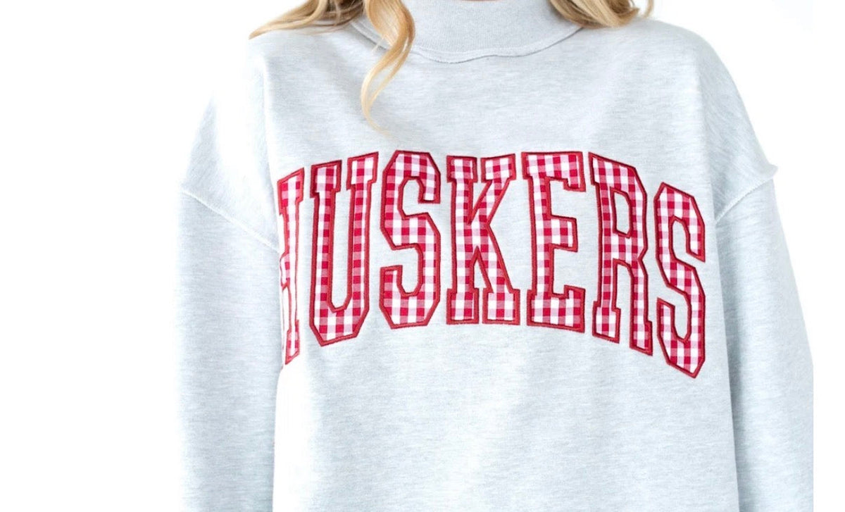 Nebraska Huskers heather gray mockneck sweatshirt with red gingham arched HUSKERS lettering and a relaxed boxy fit.