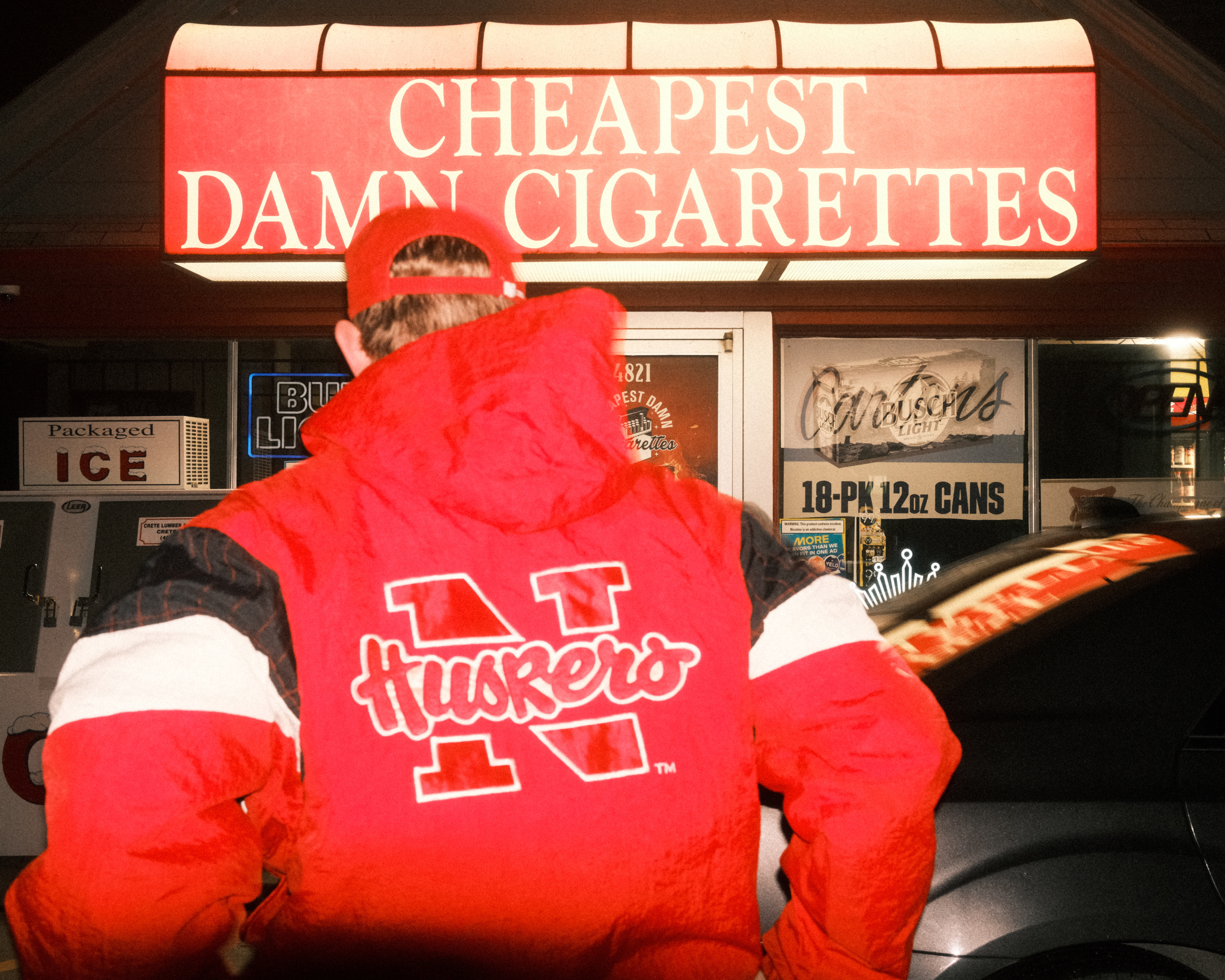 Man poses in Vintage Husker Jacket at Cheapest Damn Cigarettes in Lincoln Nebraska
