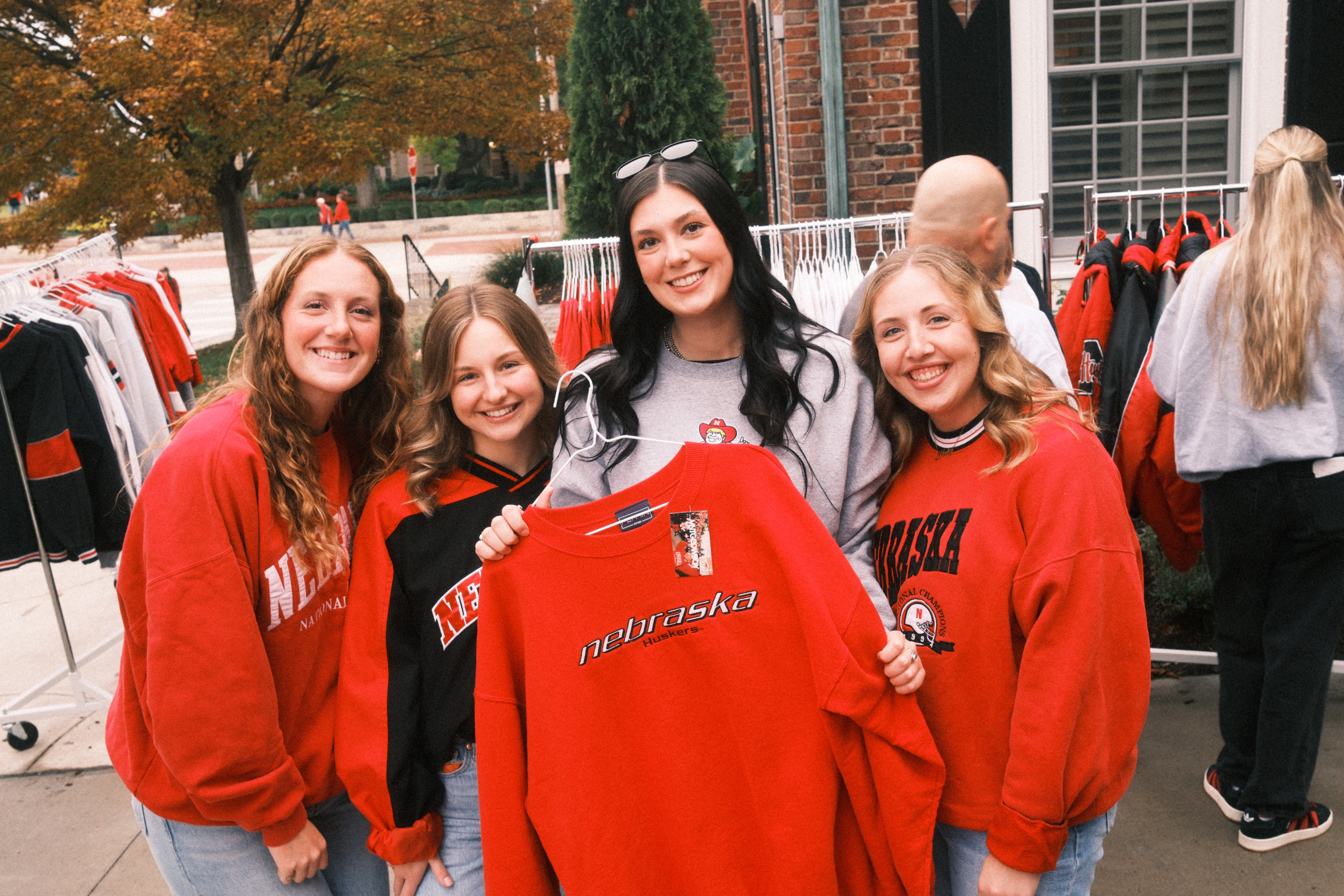 Group of shoppers holding vintage Nebraska Huskers apparel at a Vintage Cowboy campus pop-up